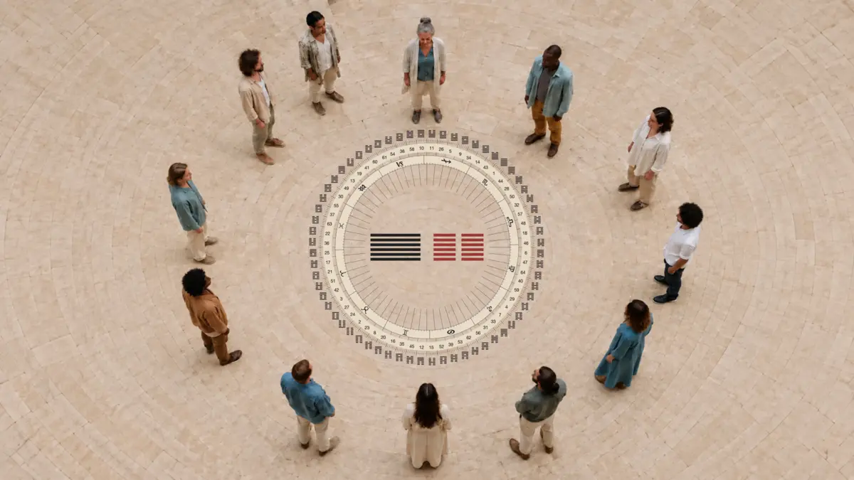 Dodici persone in cerchio attorno al Mandala Human Design con 64 esagrammi numerati e due esagrammi centrali nero e rosso.